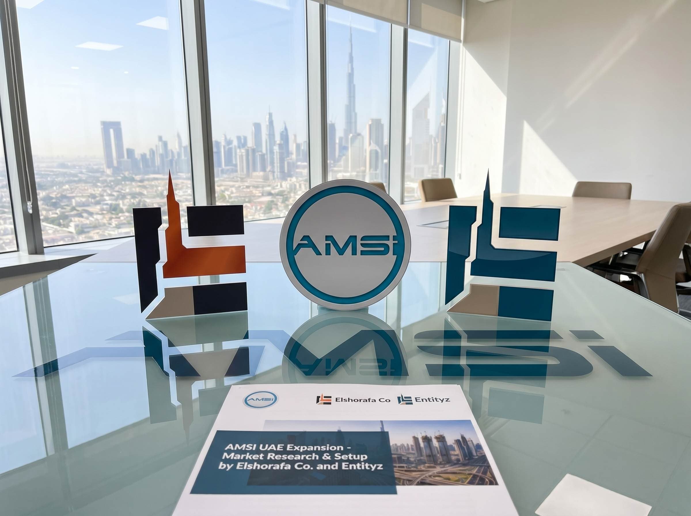 AMSI UAE market expansion partnership with Elshorafa Co and Entityz showing branded 3D logos in Dubai boardroom with Burj Khalifa skyline view representing Canadian electrical manufacturer entry into Abu Dhabi energy market